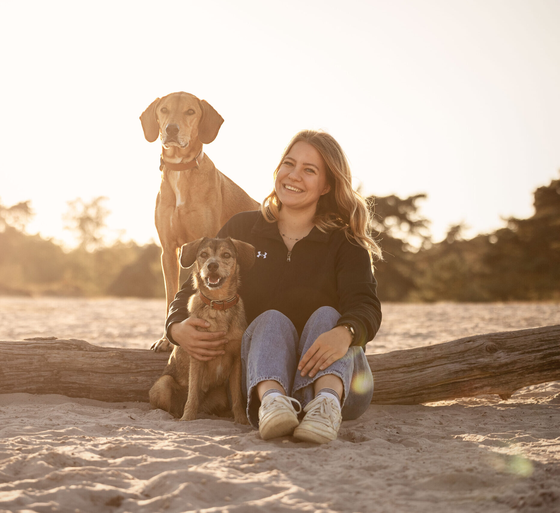 Hundetrainerin Charlotte Wessel lächelt mit ihren beiden Hunden im Arm