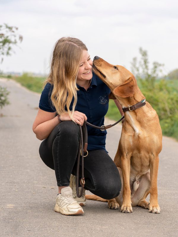 Charlotte wird von ihrem Hund im Gesicht liebkost